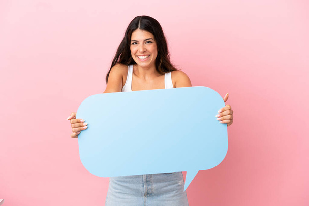 Young caucasian woman isolated on pink background holding an empty speech bubble with surprised expression - Fotografie, Obrázek