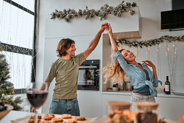 Christmas home celebration. Happy couple dancing in kitchen. Christmas mood. - Photo, Image