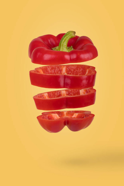 Minimal  idea with Fresh ripe sliced bell pepper floating  in air isolated on yellow background. Creative concept of food, vegetables - Fotografie, Obrázek