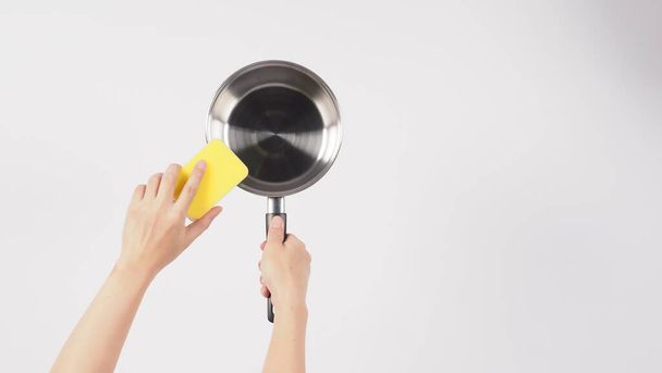 Pot cleaning. Man hand on white background cleaning the non stick pot with handy dish washing sponge which yellow color on the soft side and green on hard side for hygiene after cook. Electric pot.  - Fotó, kép