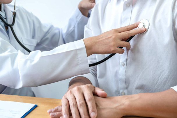 Cropped image of male doctor's hand using stethoscope to examining heartbeat and symptom of patient while talking about disease symptom and explaining treatment of the illness in clinic - Фото, зображення