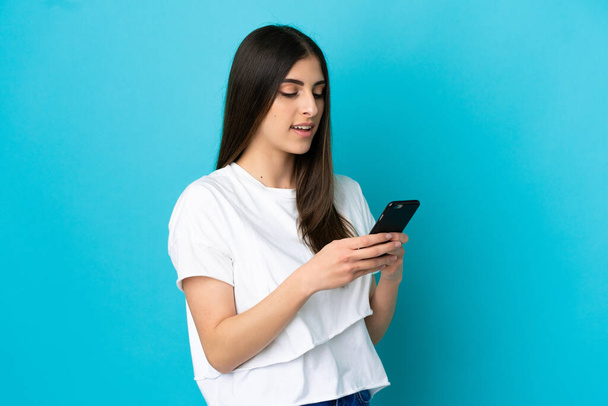 Молода біла жінка ізольована на синьому фоні, надсилаючи повідомлення або електронну пошту з мобільним телефоном
 - Фото, зображення