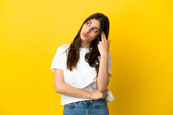 Young caucasian woman isolated on yellow background with problems making suicide gesture - Fotografie, Obrázek