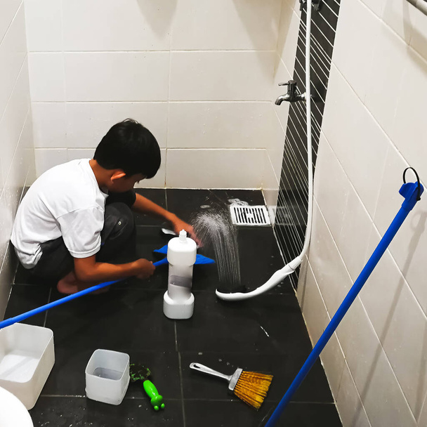 Aziatisch jongen wassen in de badkamer.Hij is met plezier in het helpen van zijn ouders met het huishoudelijk werk. - Foto, afbeelding