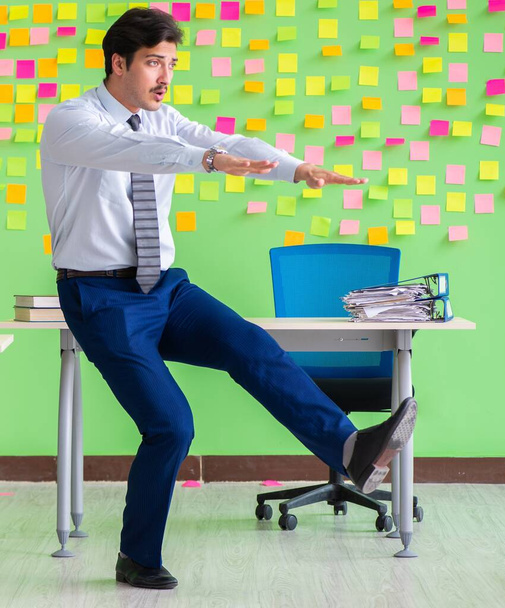 Ο άνθρωπος στο γραφείο με πολλές αντικρουόμενες προτεραιότητες κάνει ασκήσεις - Φωτογραφία, εικόνα