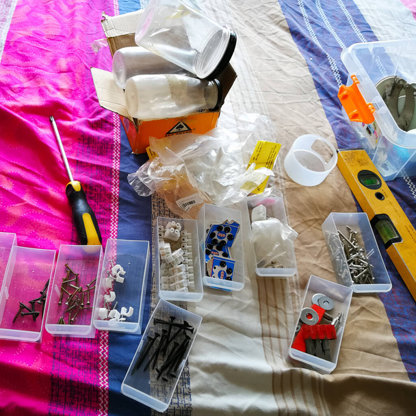 Процесс организации инструментов в контейнеры дома на кровати. - Фото, изображение