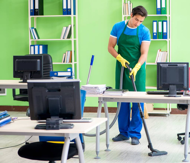 Jóképű férfi takarítás iroda porszívóval - Fotó, kép