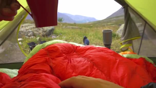 Pés homem relaxante desfrutando de montanhas com xícara de chá da entrada da barraca ao ar livre - Filmagem, Vídeo