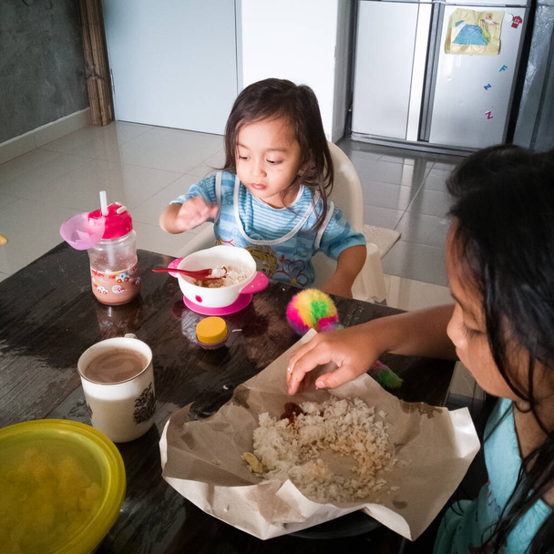 Kuala Lumpur, Malajzia - 2019. november 23.: A gyerekek otthon reggeliznek. - Fotó, kép