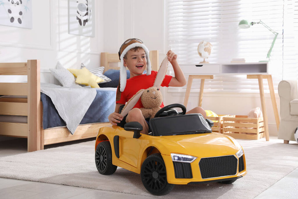 Cute little boy playing with stuffed bunny and big toy car at home - Foto, Bild