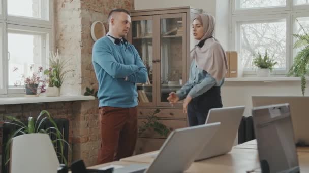 Plan PAN d'une femme musulmane dans le hijab parlant à un collègue masculin au centre d'appels - Séquence, vidéo