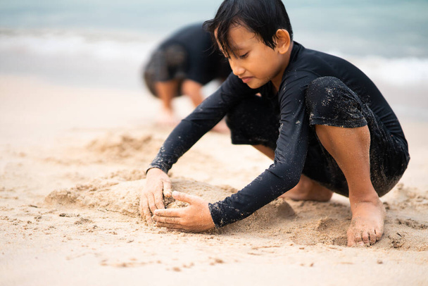 若いアジアの子供たちがビーチで遊んでいます。休暇とリラックスしたコンセプト. - 写真・画像