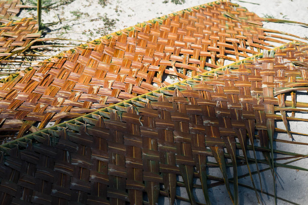 Detail of an Asian house coconut leaf basketry wall being placed on the sand for drying. - Photo, Image