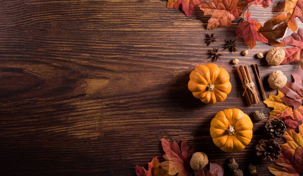 Autumn composition. Pumpkin, pine cone and autumn leaves on dark wooden background. Flat lay, top view with copy space - 写真・画像