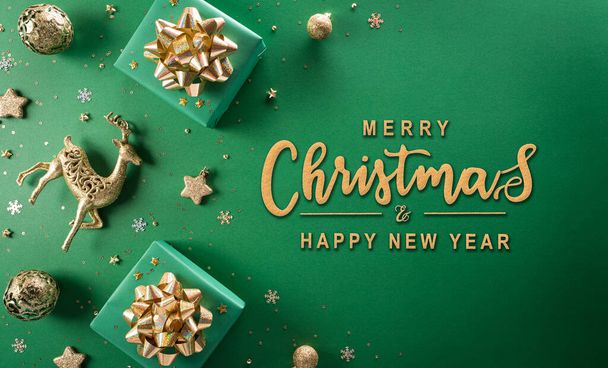 クリスマスと新年の背景の概念。クリスマスギフトボックス、トナカイ、クリスマスボール、雪の結晶のトップビューと緑の背景のテキスト. - 写真・画像