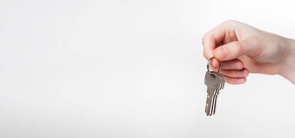 Hand holding keys on keyring over white background. Promo banner for real estate advertising with copy space for text - Foto, Bild