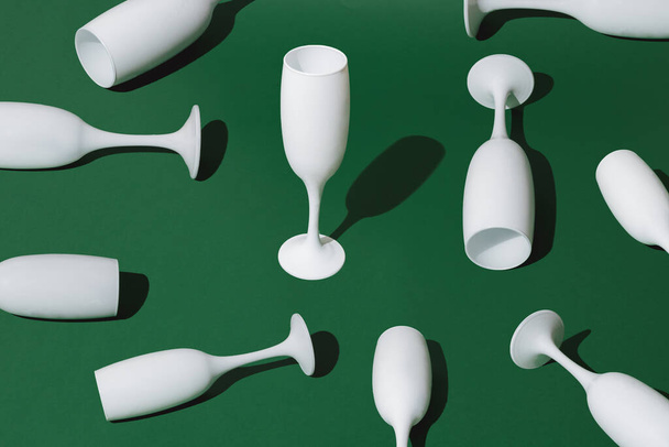 Arranged white champagne glasses on green pastel background. Minimal pattern and concept. - Zdjęcie, obraz