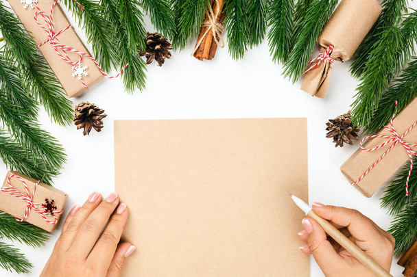 The concept of letter to Santa Claus. Woman hands on craft paper in frame of Christmas trees with decorations - Foto, immagini