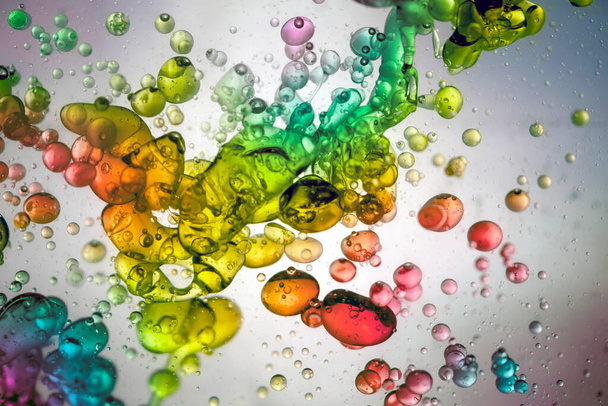 Gotas de agua de muchos colores formando burbujas y flotando en lquido transparente - Photo, Image