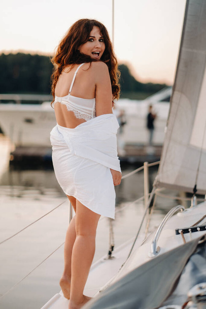 donna sexy in camicia bianca gode il tramonto sul suo yacht bianco privato. - Foto, immagini
