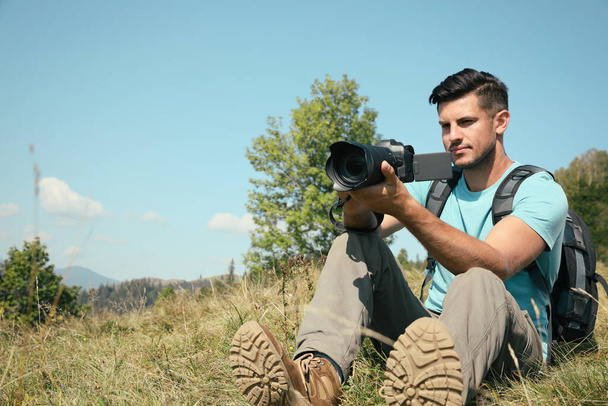 Fotógrafo profesional tomando fotos con cámara moderna en las montañas. Espacio para texto - Foto, Imagen