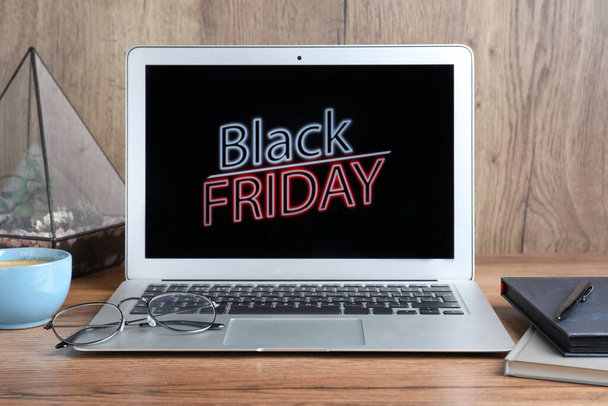 Laptop, cup of coffee and stationery on wooden table. Black Friday sale - 写真・画像