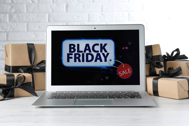 Laptop and gift boxes on white wooden table. Black Friday sale - Fotoğraf, Görsel