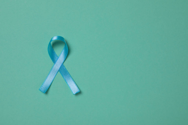 Light blue awareness ribbon on turquoise background, top view. Space for text - Fotoğraf, Görsel