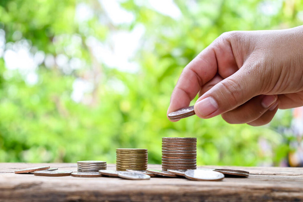 Mãos humanas segurando moedas e pilhas de moedas no chão de madeira ideias financeiras e de investimento. - Foto, Imagem
