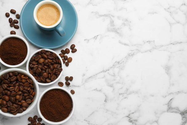 Κόκκοι καφέ, σκόνη και ένα φλιτζάνι ποτό σε λευκό μαρμάρινο τραπέζι, επίπεδο lay. Χώρος για κείμενο - Φωτογραφία, εικόνα