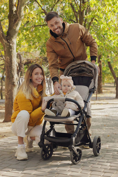 Happy parents walking with their baby in stroller at park on sunny day - Foto, immagini