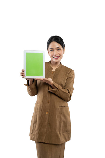 Attractive woman wearing khaki uniform smiling showing her tablet screen - Photo, image