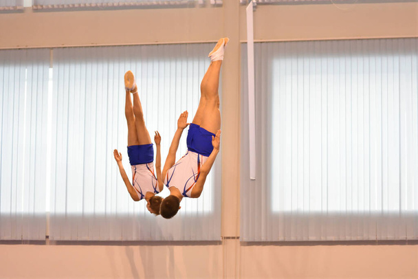 Два мальчика тренируются в синхронном прыжке на батуте  - Фото, изображение
