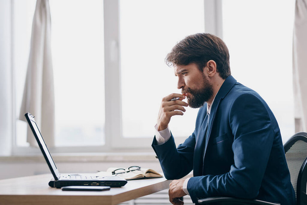 hombre en frente de la computadora portátil en la oficina delante de un gerente ejecutivo portátil - Foto, imagen