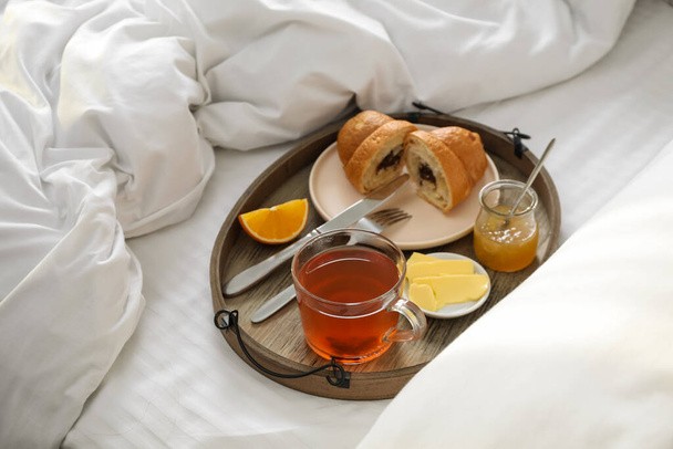 Tray with tasty breakfast on bed in morning - Foto, afbeelding