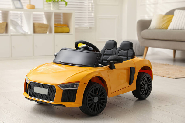 New yellow toy car in living room - Foto, afbeelding