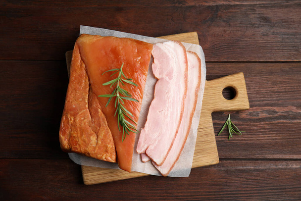 Delicious smoked bacon with rosemary on wooden table, flat lay - Φωτογραφία, εικόνα