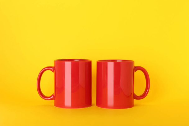 Blank red ceramic mugs on yellow background - Photo, Image