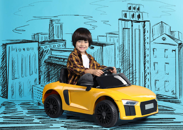 Cute little boy driving toy car and drawing of city on light blue background - Foto, Bild