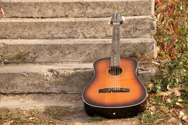 old brown guitar lies in the park on the steps in the fall in the sun, guitar - Photo, Image