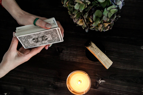 tarot cards in hands on a dark background in the light of a candle - Foto, imagen