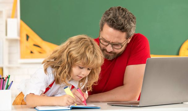 преподаватель и ребенок в классе с ноутбуком, семьей - Фото, изображение