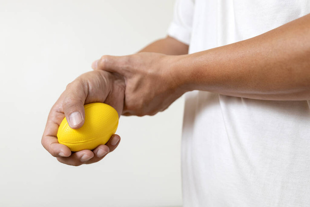 Hands of asian male holding a stress ball,man patient doing hand and wrist exercise,training with rubber ball,squeezing for muscle strength,treatment of hand finger weakness,physical therapy,recovery - Photo, Image