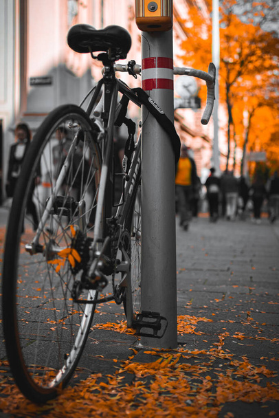 A vertical shot of a bicycle locked near the column in the street - 写真・画像