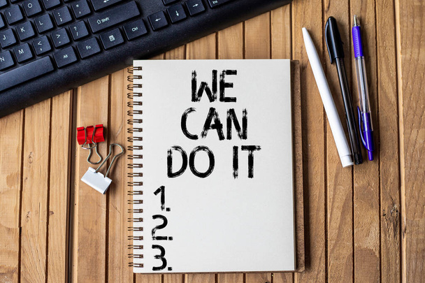 Texte inspirant We Can Do It. Concept signifiant que vous vous voyez comme une personne puissante capable Journal ouvert clippé vide à côté des stylos de clavier sur le dessus du bureau en bois. - Photo, image