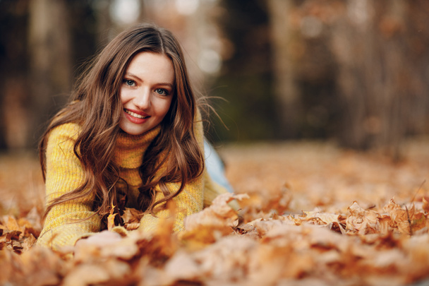 Jonge vrouw model in het najaar park met geel blad esdoorn bladeren. Herfstseizoen mode. - Foto, afbeelding