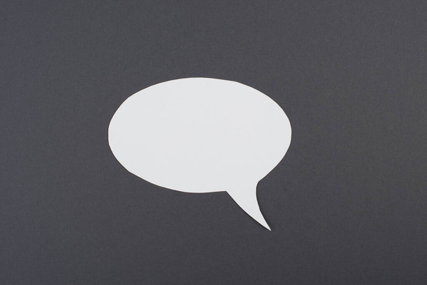 Empty speech bubble, white paper on a dark grey background, copy space for text, communication symbol - 写真・画像