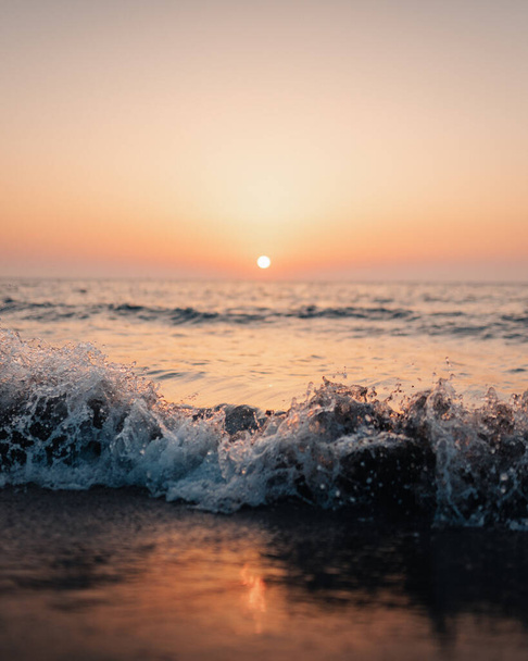 A vertical shot of waves of the sea on the sunset sky background - Foto, afbeelding
