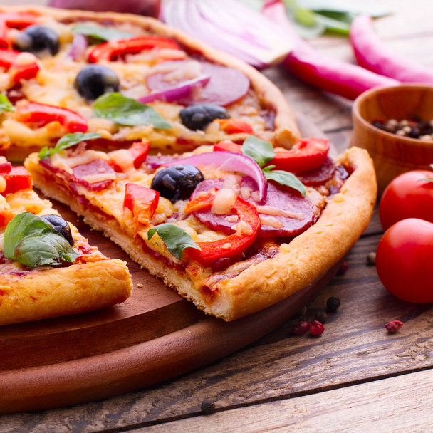Pizza with ham, pepper and olives. Delicious fresh pizza served on wooden table. - 写真・画像