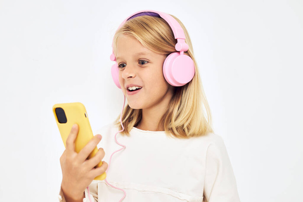 χαριτωμένο κορίτσι σε ροζ ακουστικά τηλέφωνο - Φωτογραφία, εικόνα